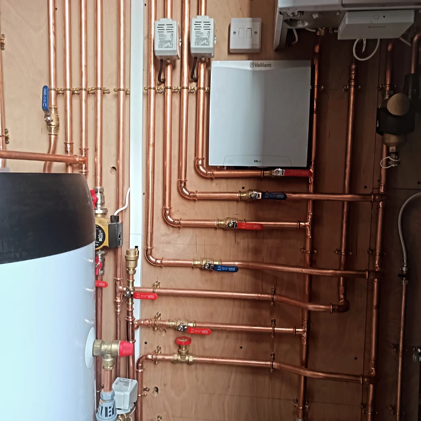 A hot-water cylinder and controls, plumbed in tidily.